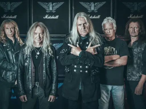 Le groupe Saxon, cinq musiciens aux cheveux longs, pose devant des amplis Marshall.