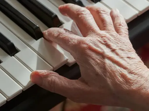 Main d'une personne âgée jouant du piano, un instrument facile à apprendre pour adulte.