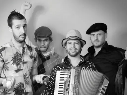 Le groupe java, avec son accordéoniste au centre, pose joyeusement. L'un des musiciens lève le poing, l'autre fait un clin d'œil.