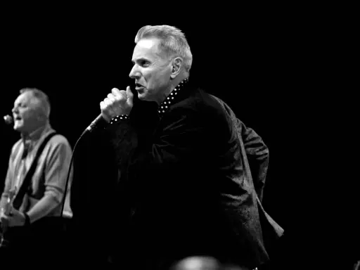 Le chanteur, comme un Dr Feelgood, captive la foule avec sa voix puissante. Un guitariste l'accompagne sur scène.