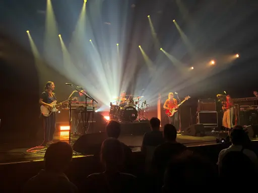 Une goat girl joue de la guitare sur scène, éclairée par des projecteurs.
