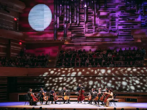 Un orchestre joue sur scène, éclairé par une lune projetée. C'est quoi un single ? Une pièce musicale unique, comme un solo d'un musicien.