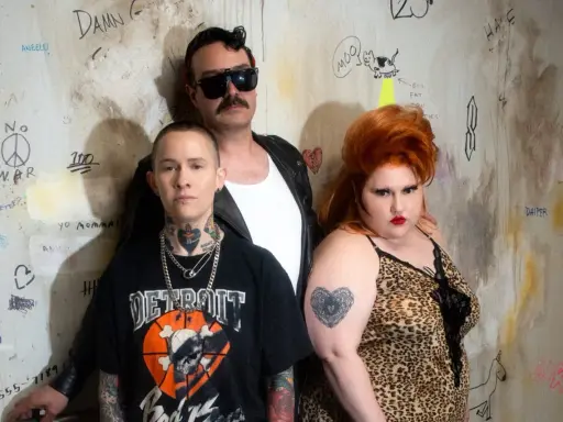 Un groupe d'amis, un vrai gossip groupe, pose devant un mur tagué. L'un porte un t-shirt "Detroit", l'autre une robe léopard, le troisième des lunettes de soleil.
