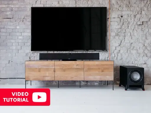 Un salon moderne avec une TV, une barre de son et un **pre out subwoofer** noir sur un meuble en bois.