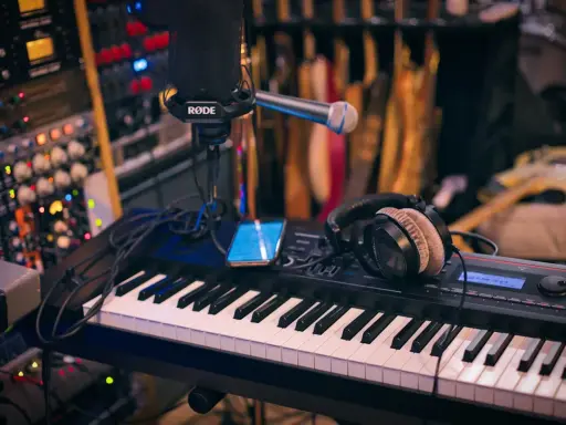 Clavier, micro, casque et smartphone sur un bureau de mixage. L'équipement parfait pour savoir comment se lancer dans la musique.