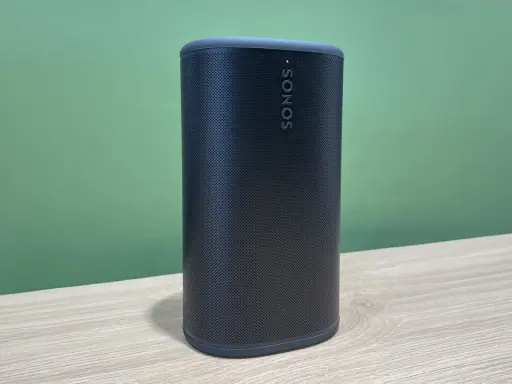 Enceinte Sonos noire sur une table en bois, prête à diffuser votre musique bluetooth préférée.