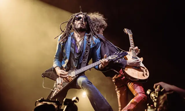 Lenny Kravitz, icône du rock, joue de la guitare sur scène, une image qui pourrait figurer sur un album.