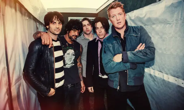 Les membres de Queens of the Stone Age posent ensemble, un groupe de rock emblématique.