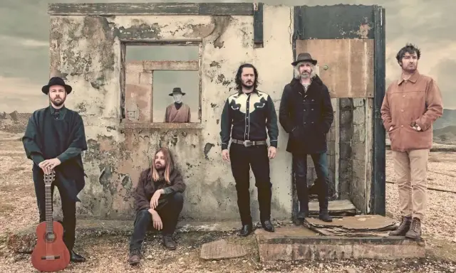 Cinq hommes posent devant une ruine. L'un tient une guitare. Une silhouette dans une fenêtre rappelle le corail, mer de miroirs.