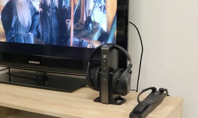 Un téléviseur Samsung diffuse un film, avec un casque sans fil sur son socle à côté. Idéal pour profiter du son tv et casque en même temps.