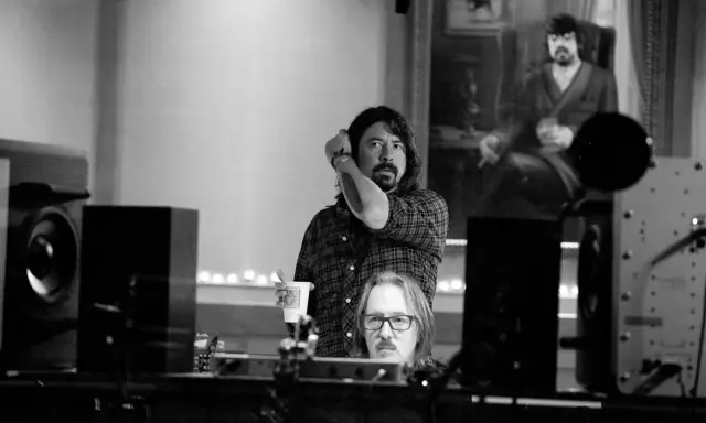 Dans ce studio d'enregistrement, deux hommes sont entourés d'équipements audio, créant une ambiance de **sound city**.
