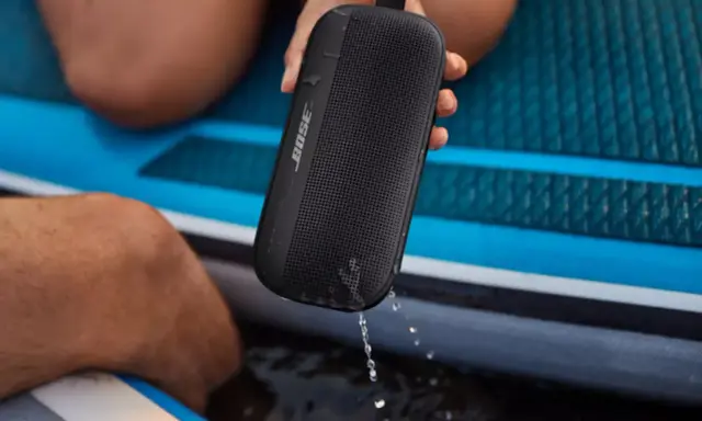 Enceinte Bose noire, étanche IPX4, éclaboussée par la pluie sur un paddleboard.