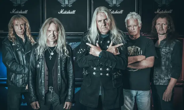 Le groupe Saxon, cinq musiciens aux cheveux longs, pose devant des amplis Marshall.