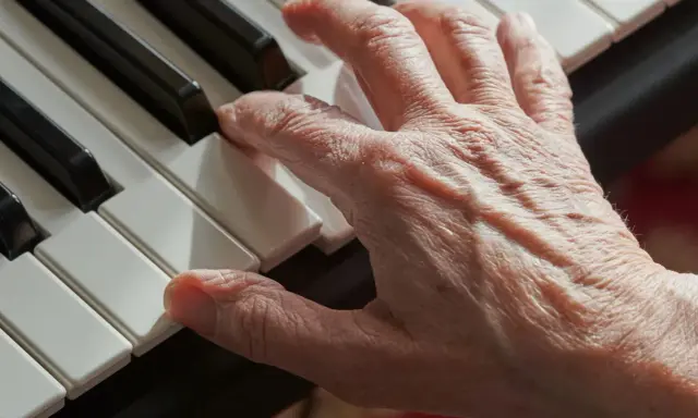 Main d'une personne âgée jouant du piano, un instrument facile à apprendre pour adulte.