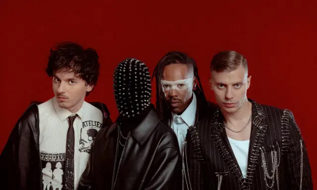 Les membres de Skip the Use posent sur fond rouge, avec des looks audacieux et stylisés.