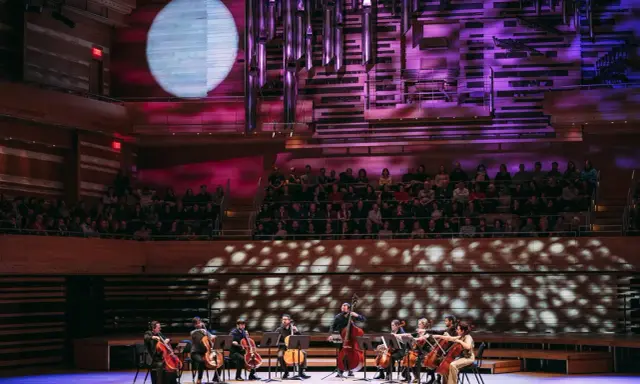 Un orchestre joue sur scène, éclairé par une lune projetée. C'est quoi un single ? Une pièce musicale unique, comme un solo d'un musicien.