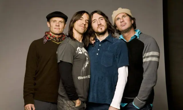 Les membres des Red Hot Chili Peppers posent ensemble, un groupe de rock légendaire.