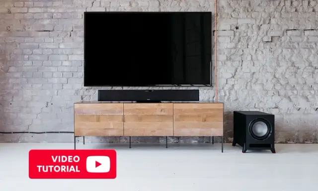 Un salon moderne avec une TV, une barre de son et un **pre out subwoofer** noir sur un meuble en bois.