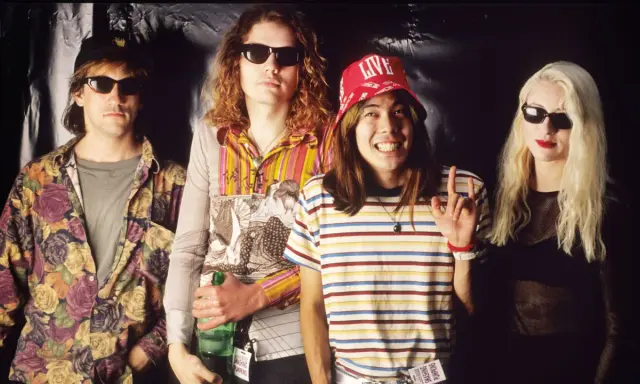 D'arcy Wretzky 2023, icône rock, pose avec les Smashing Pumpkins. Le groupe, dans un style années 90, arbore des tenues colorées et des lunettes de soleil.