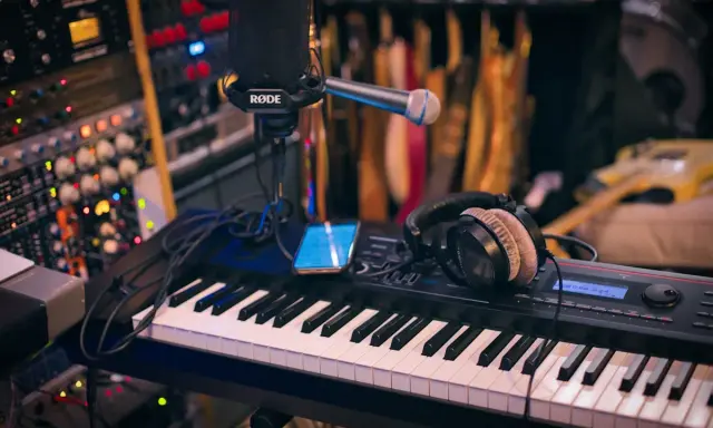 Clavier, micro, casque et smartphone sur un bureau de mixage. L'équipement parfait pour savoir comment se lancer dans la musique.