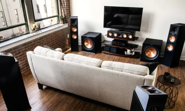 Salon moderne avec canapé clair, TV et système audio Klipsch pour une expérience sonore immersive, que ce soit en PCM ou Dolby Digital.