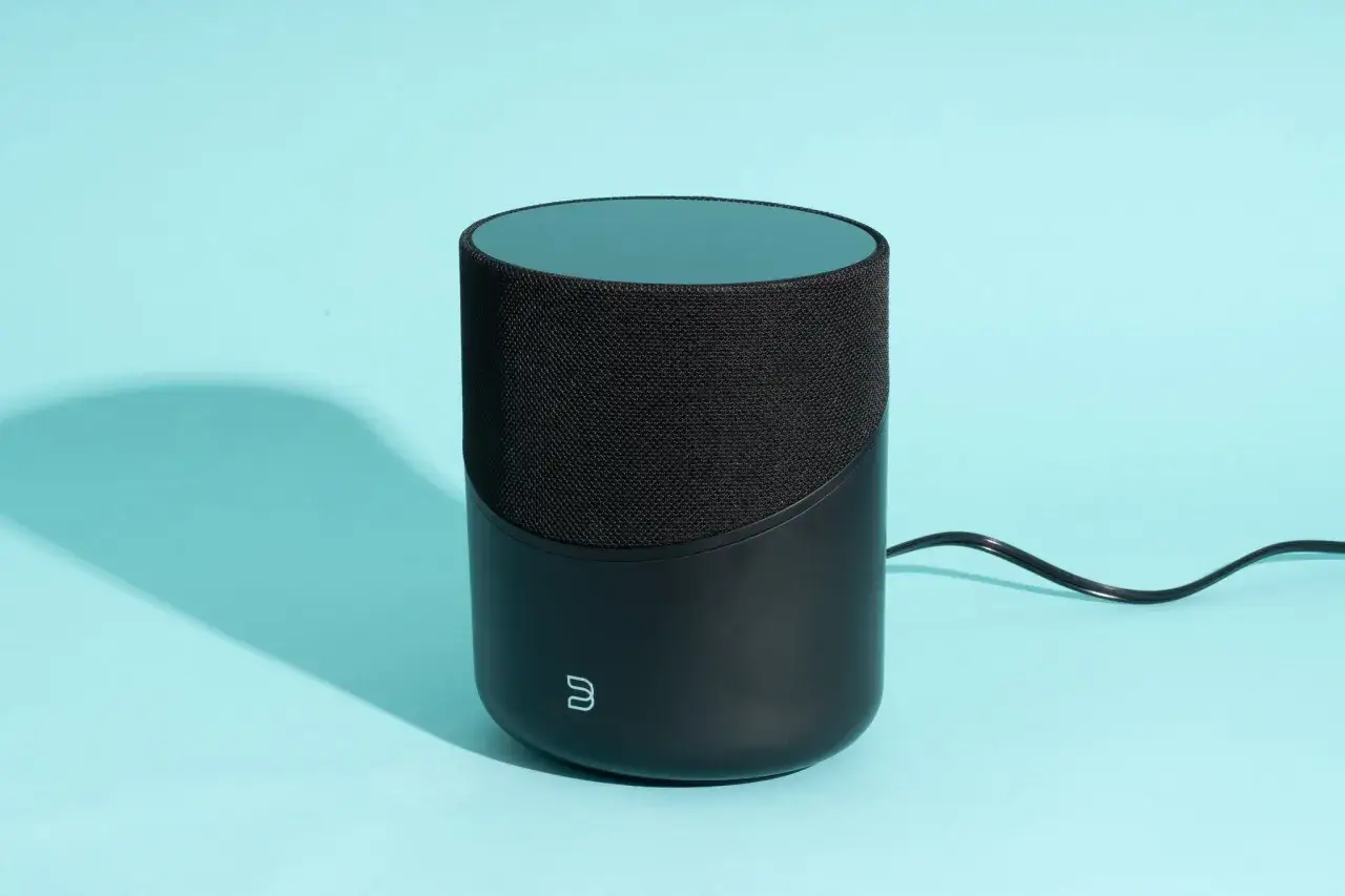 Enceinte noire cylindrique avec logo, prête pour l'airplay 2. Son design moderne s'intègre parfaitement dans votre intérieur.