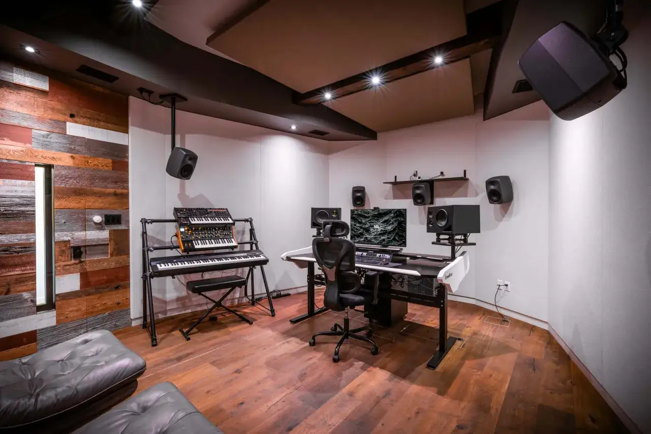 Studio d'enregistrement moderne avec claviers, moniteurs et fauteuils en cuir. Idéal pour savoir comment trouver un producteur de musique.