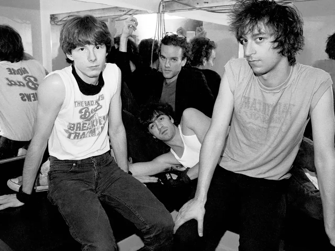 Le groupe rem, en noir et blanc, pose pour une photo. Les membres portent des t-shirts et des jeans.