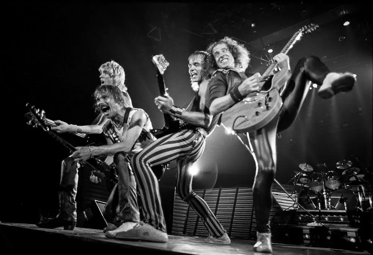 Le groupe Scorpion en pleine performance, des guitaristes en action sur scène, une énergie rock'n'roll palpable.