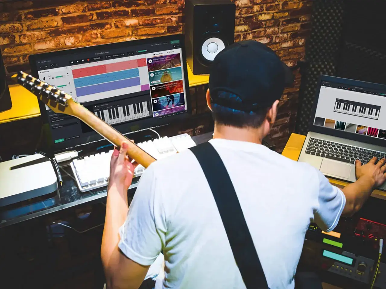Un musicien compose en ligne, guitare en main, devant un écran affichant une table de mixage et un clavier virtuel.