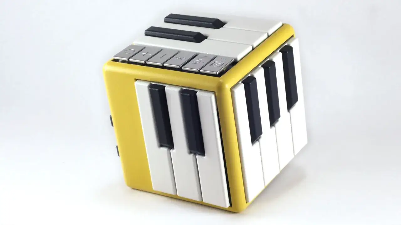 Un petit instrument de musique en forme de cube jaune avec des touches de piano sur plusieurs faces.