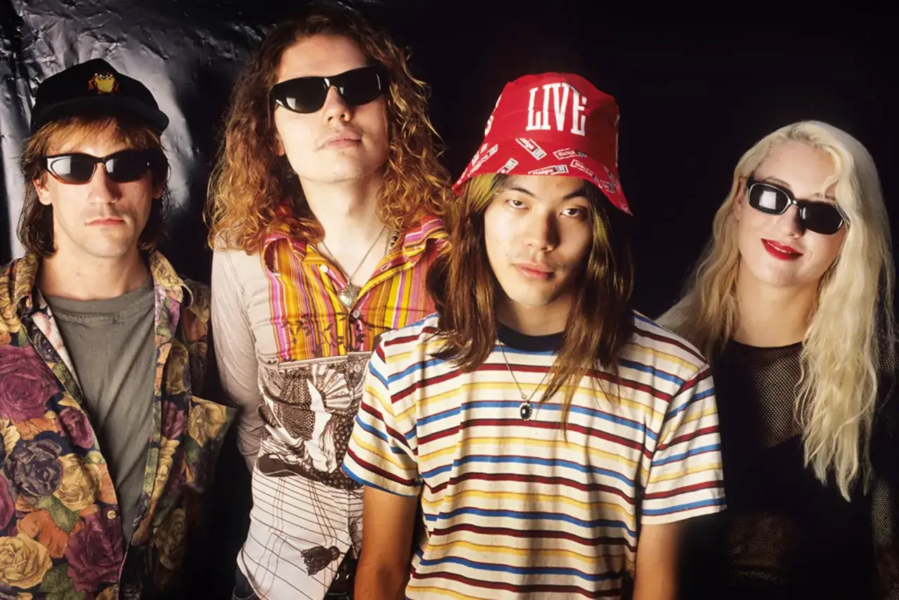 D'Arcy Wretzky 2023, membre du groupe Smashing Pumpkins, pose avec ses acolytes, arborant un style décontracté et coloré.