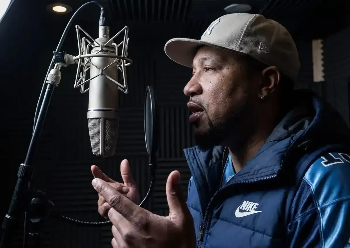 Un homme apprend &agrave; rapper dans un studio d'enregistrement, parlant dans un microphone professionnel.