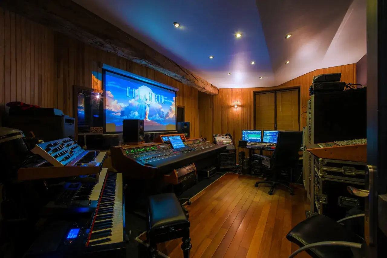 Studio d'enregistrement avec claviers, console de mixage et écran projetant le logo Columbia. Un endroit idéal pour apprendre comment se lancer dans la musique.