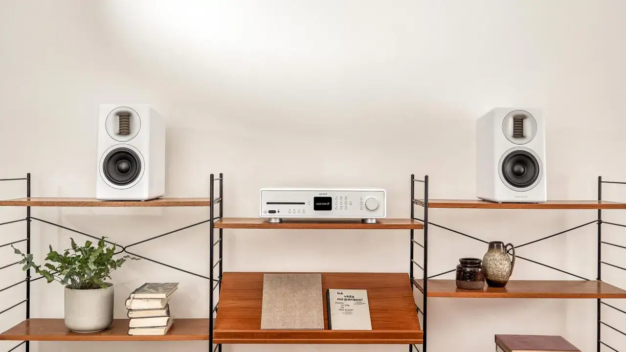 Deux enceintes hifi blanches sur des étagères en bois, avec un appareil audio au centre. Le placement enceinte hifi est soigné.