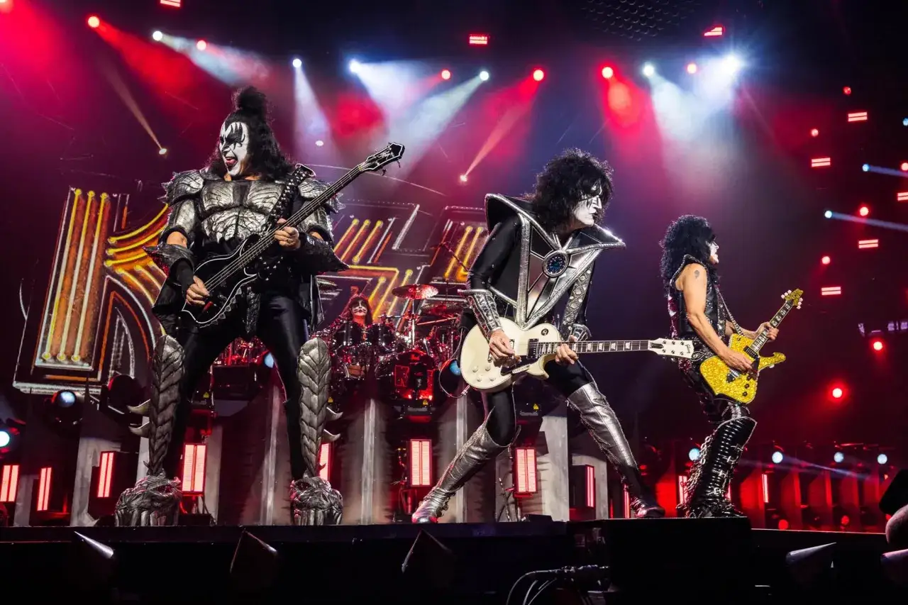 Le groupe KISS en concert, avec leurs costumes iconiques et leurs maquillages spectaculaires, enflamme la sc&egrave;ne sous des jeux de lumi&egrave;re intenses.