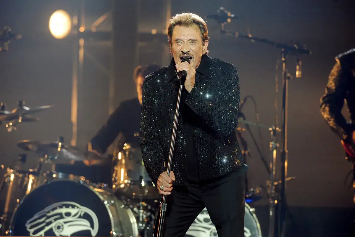 Johnny Hallyday, en scène, micro en main, étincelant. On se demande combien gagne un musicien de Johnny Hallyday.