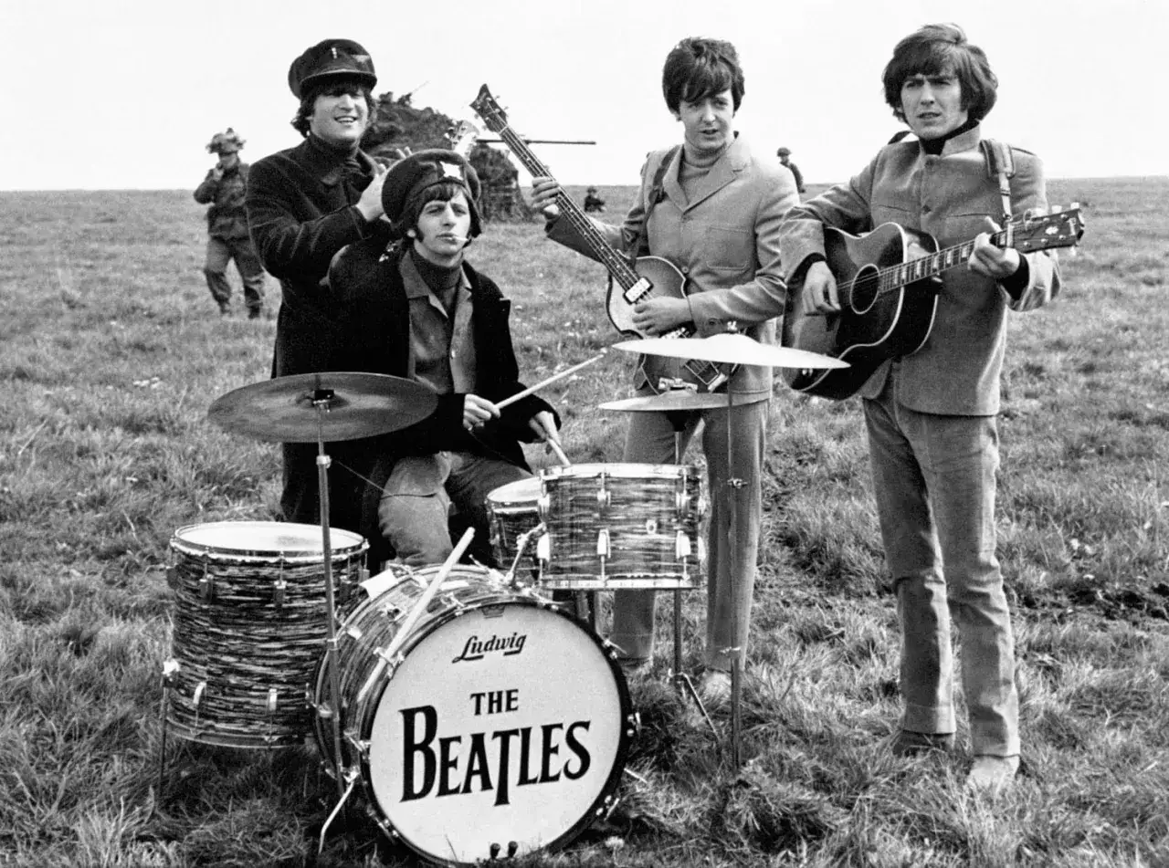 Les Beatles jouent en plein air. Ringo frappe la batterie, John et Paul jouent de la guitare, George est aussi pr&eacute;sent.
