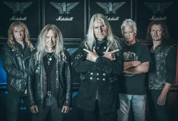 Le groupe Saxon, cinq musiciens aux cheveux longs, pose devant des amplis Marshall.