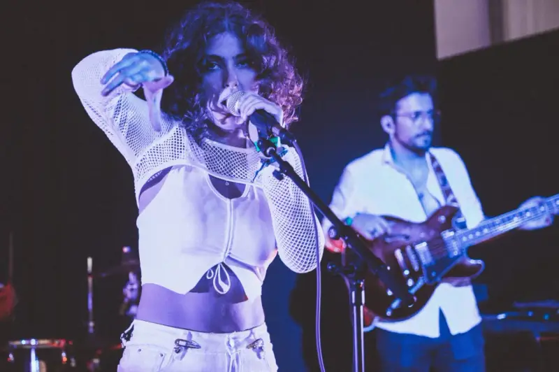 Une chanteuse au look audacieux, micro en main, semble exprimer son dédain pour une chanson nulle. Un guitariste l'accompagne sur scène.