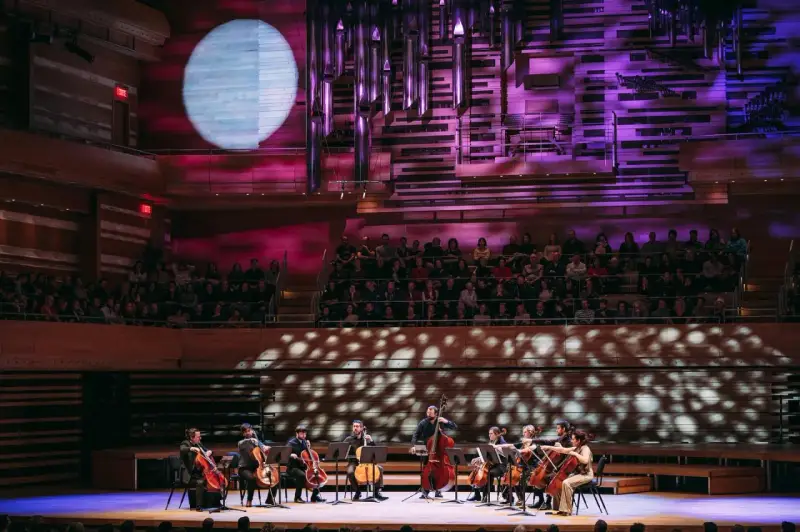 Un orchestre joue sur scène, éclairé par une lune projetée. C'est quoi un single ? Une pièce musicale unique, comme un solo d'un musicien.